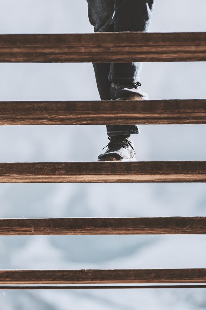 Low angle view capturing feet in motion on a wooden staircase, symbolizing movement.